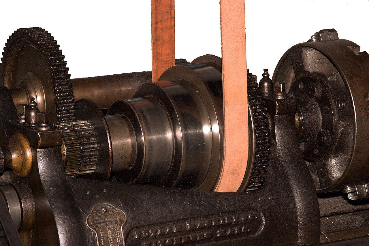 Stepped cone pulleys with a flat leather belt on a lathe headstock — shifting the belt between steps is one way to increase pulley RPM without buying new pulleys